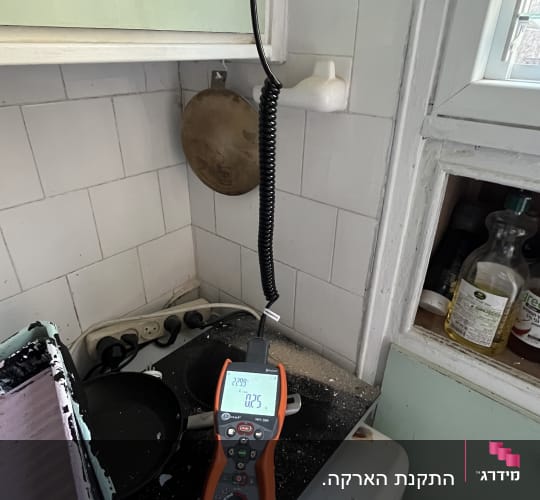 מד מתח חשמלי מחובר לשקע במטבח